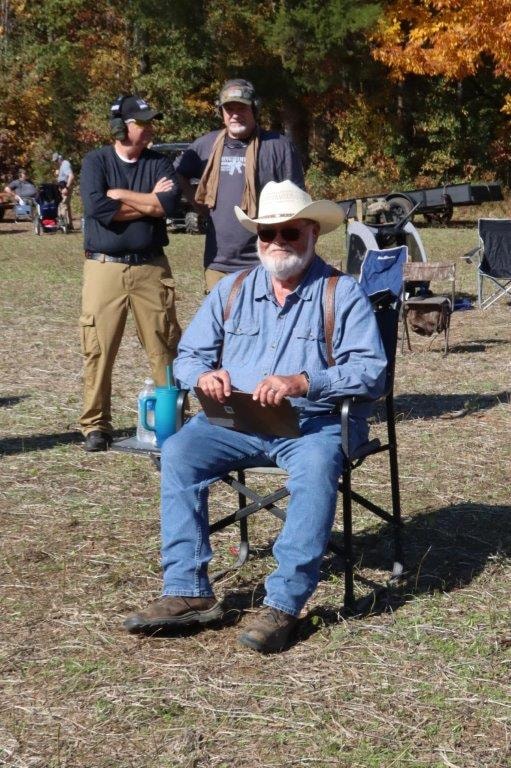 Event volunteer seated outdoors with competitors in the background
