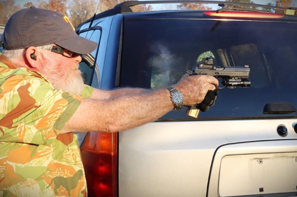 Competitor aiming a handgun beside a vehicle