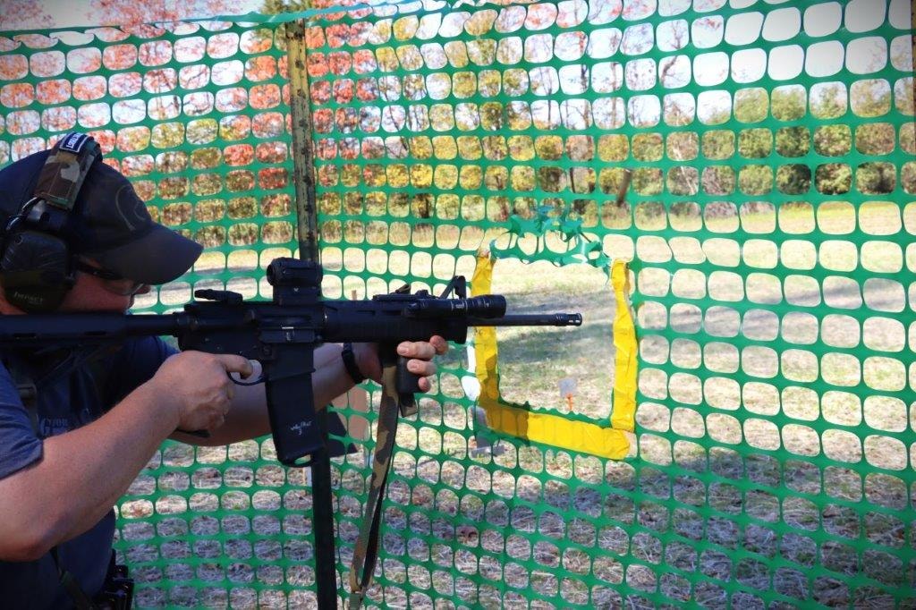 Competitor using a rifle through green safety netting at an outdoor range