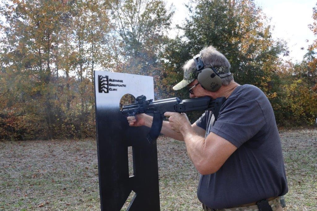 Competitor at a shooting stage beside a sponsor target