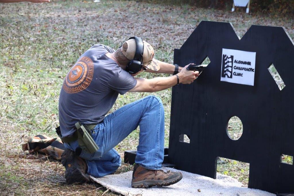Competitor kneeling beside a sponsor target at the range